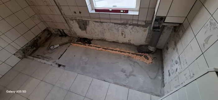 Plek van oud bad onder het raam gesloopt, nieuwe afvoer ingefreesd in de vloer