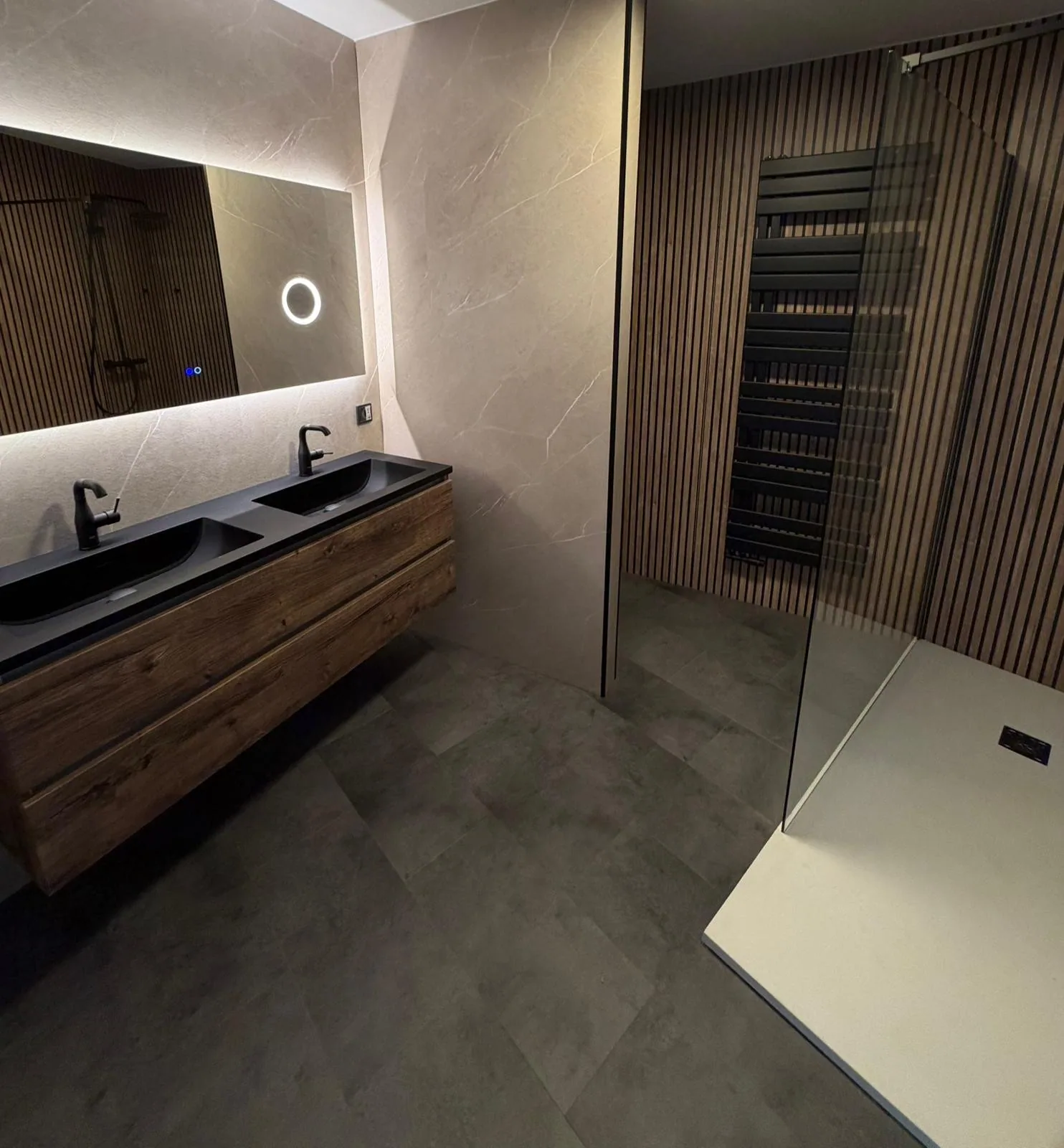Badkamer met dubbel meubel en inloopdouche Badkamer met zwevend houten dubbel wastafelmeubel, zwarte wastafels, LED-spiegel en inloopdouche met houten lamellenwand