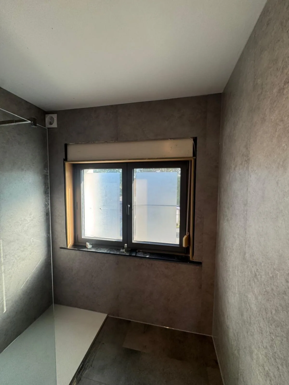Grijze wandpanelen rondom Badkamer rondom bekleed met grijze stenen-look wandpanelen, raam en inloopdouche met witte douchebak