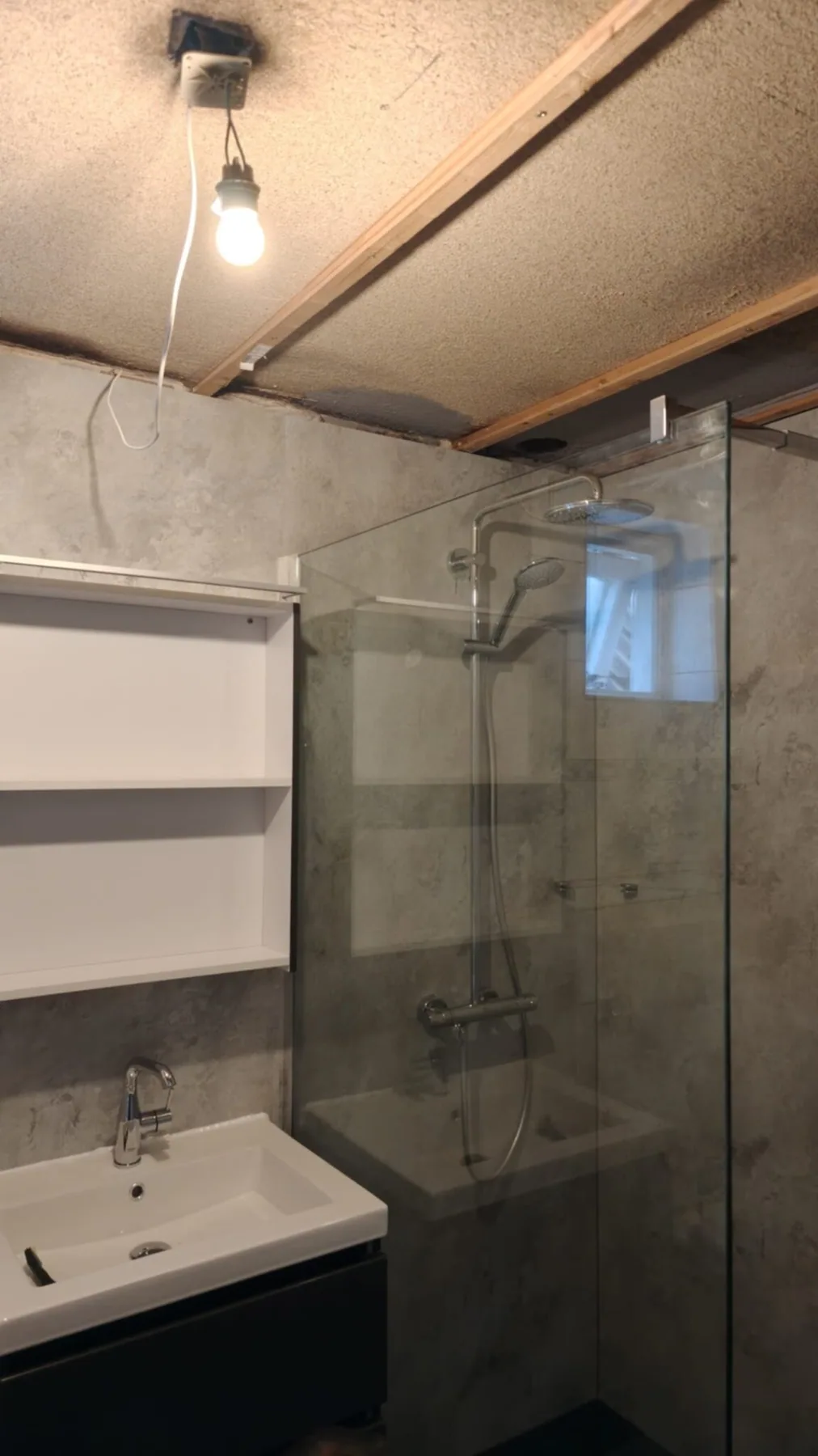 Badkamer met inloopdouche Badkamer met inloopdouche, glazen wand, betonlook panelen en wastafel met open kast