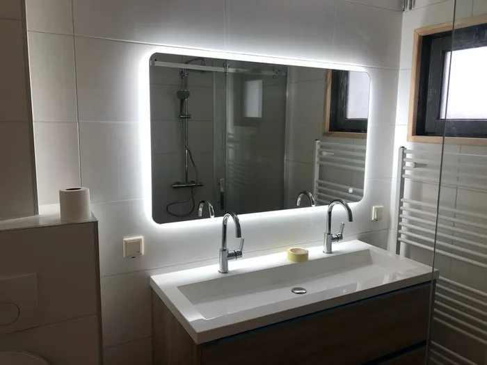 LED-spiegel boven dubbele wastafel Badkamer met verlichte LED-spiegel boven dubbele wastafel, inloopdouche zichtbaar in de spiegel