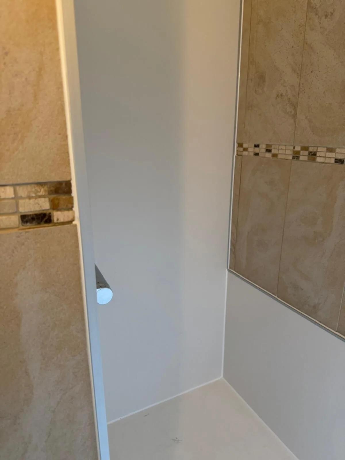 Douchenis met witte wandpanelen Nieuwe witte wandpanelen en douchevloer in douchenis naast bestaande beige tegels met mozaïekrand