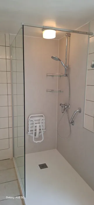 Seniorendouche met zitje Inloopdouche met lichte wandpanelen, opklapbaar douchezitje, steunbeugel en glazen wand