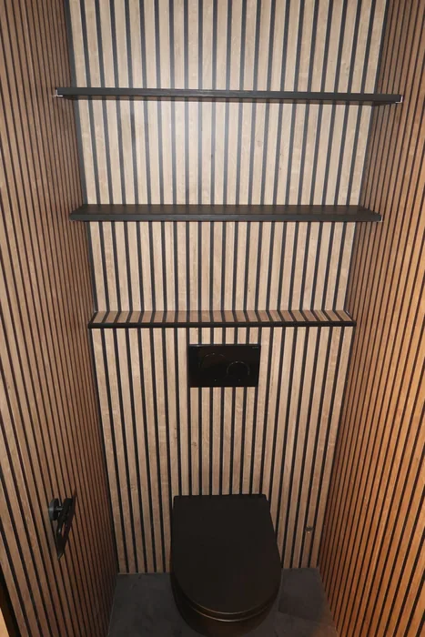 Toilet met lamellenwand en zwart hangtoilet Toilet met houten lamellenwanden, zwart hangtoilet, zwarte bedieningsplaat en zwarte wandplanken